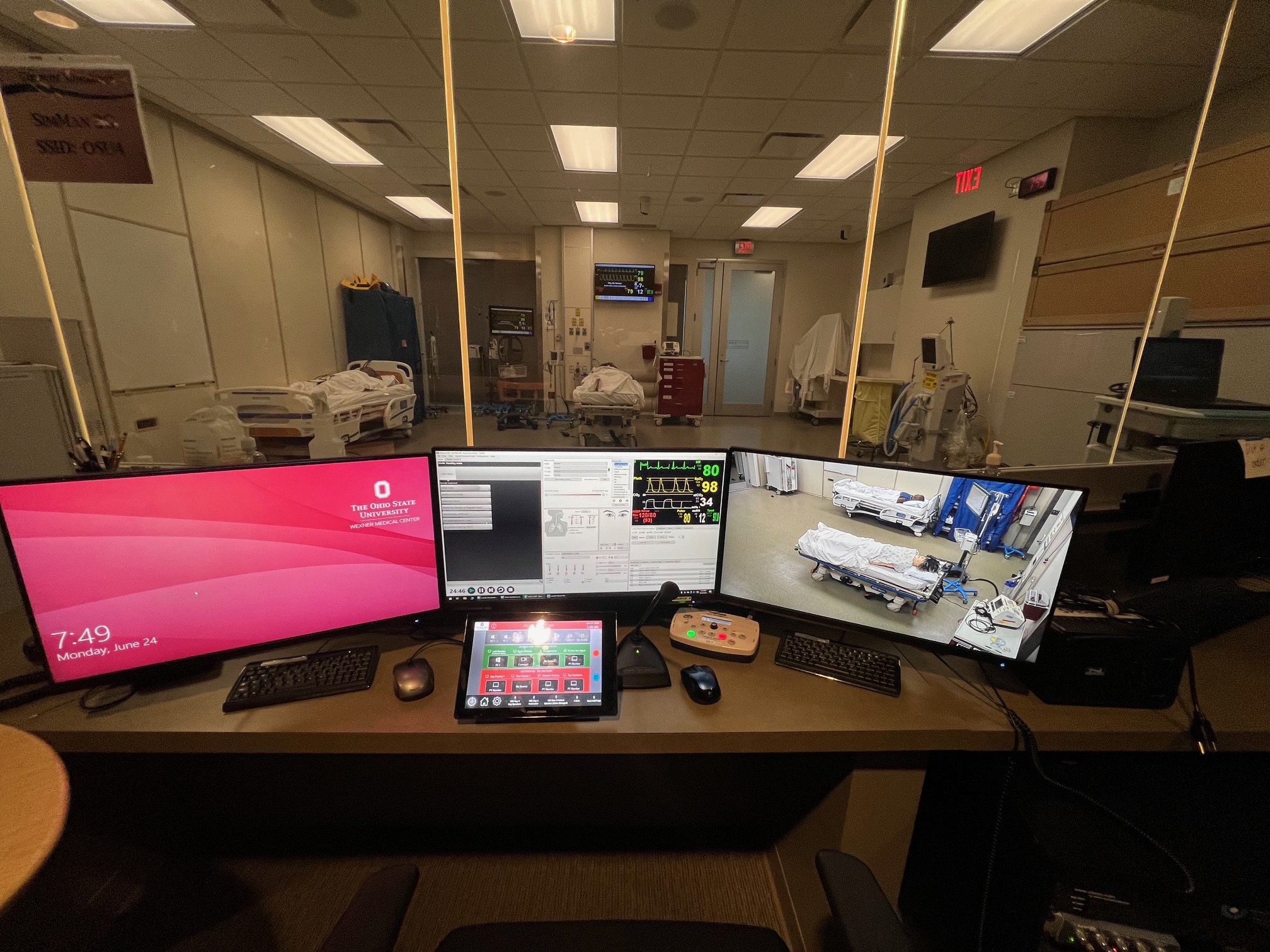 Simulation center control room with multiple monitors overlooking simulation lab